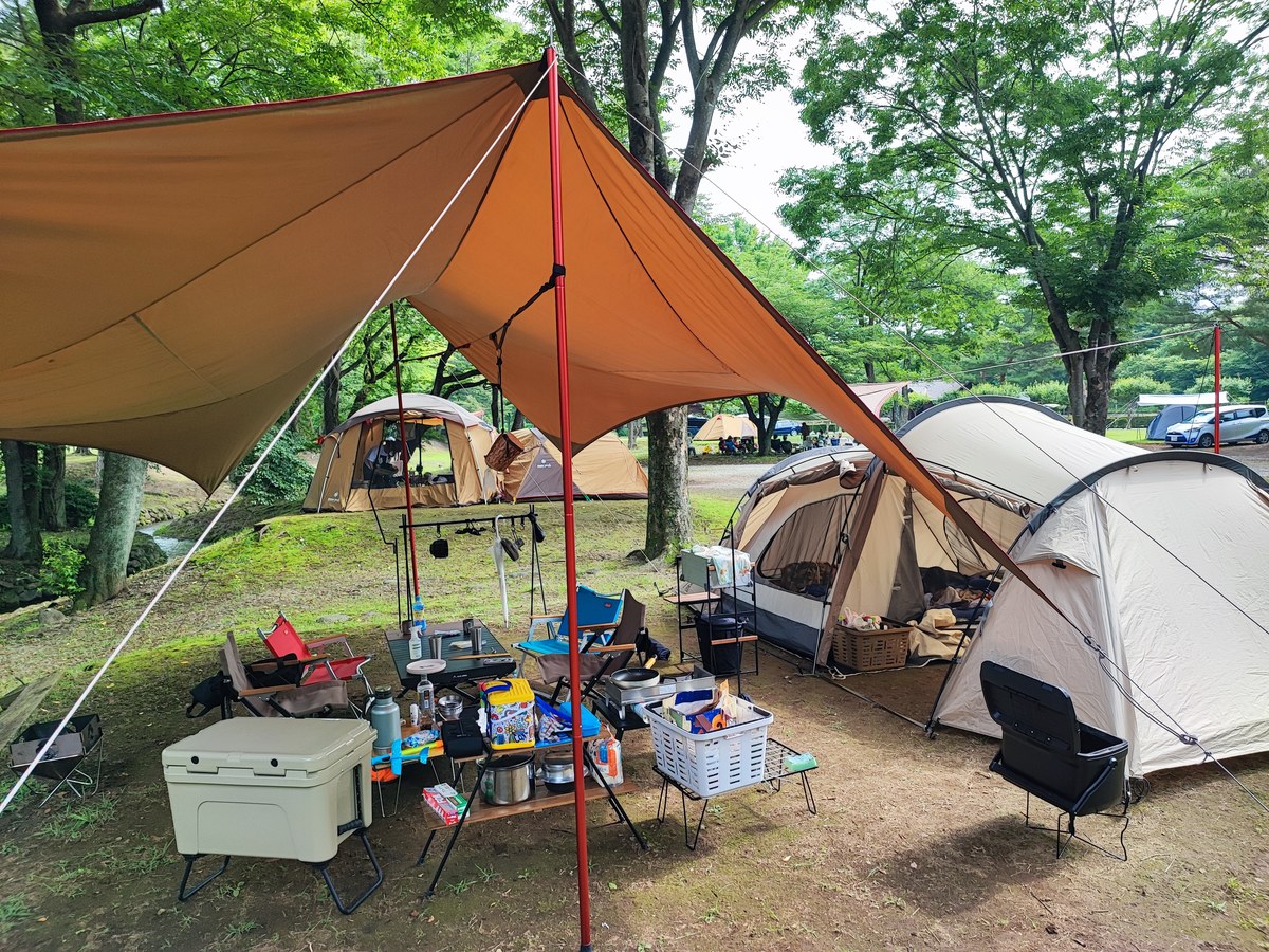 雨の日でも広いタープ下で快適に過ごすファミリーキャンプの様子